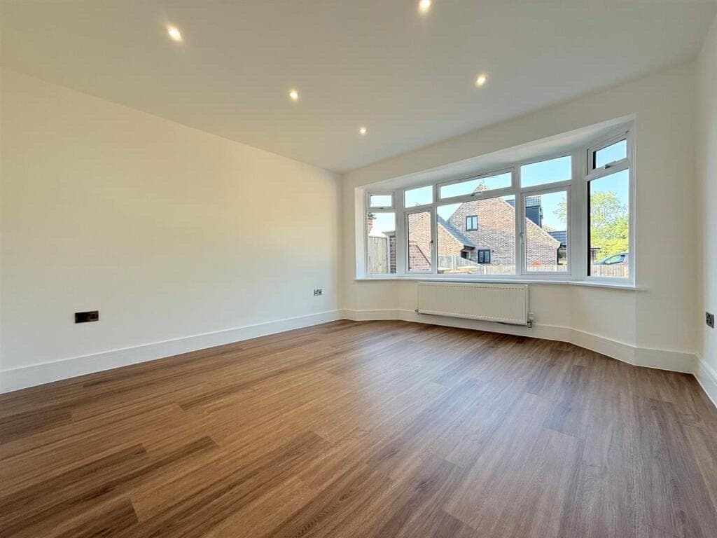 Dark warm oak LVT plank flooring in a living room with a wide bay window looking onto neighbouring rooftops