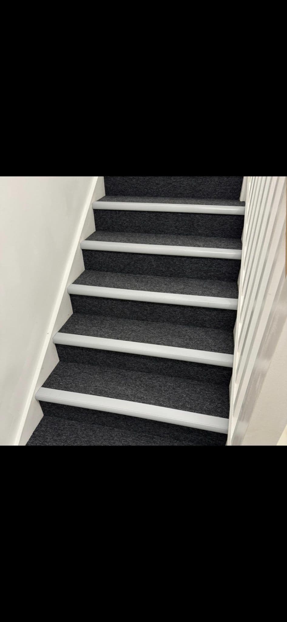 Charcoal contract carpet fitted to a staircase with white slip-resistant nosings on every step